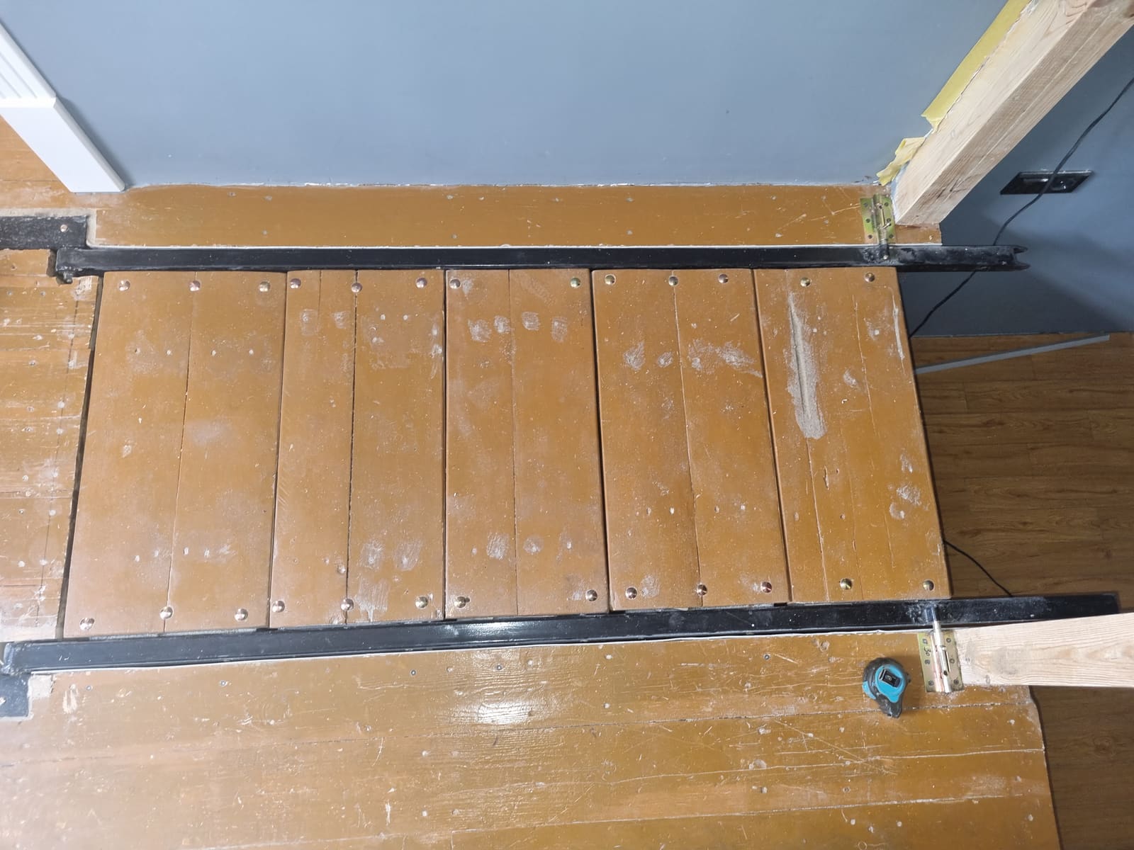 Closed pose from above — six treads tiled flush into the floor opening between the black steel rails